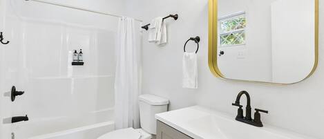 A bathroom with a bathtub, toilet, sink, and a mirror with a gold frame.