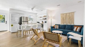 A modern kitchen with white cabinetry, a built-in oven, and a dining area with white chairs and a wooden bench. - Mystic Woods Trio Branson (Branson)