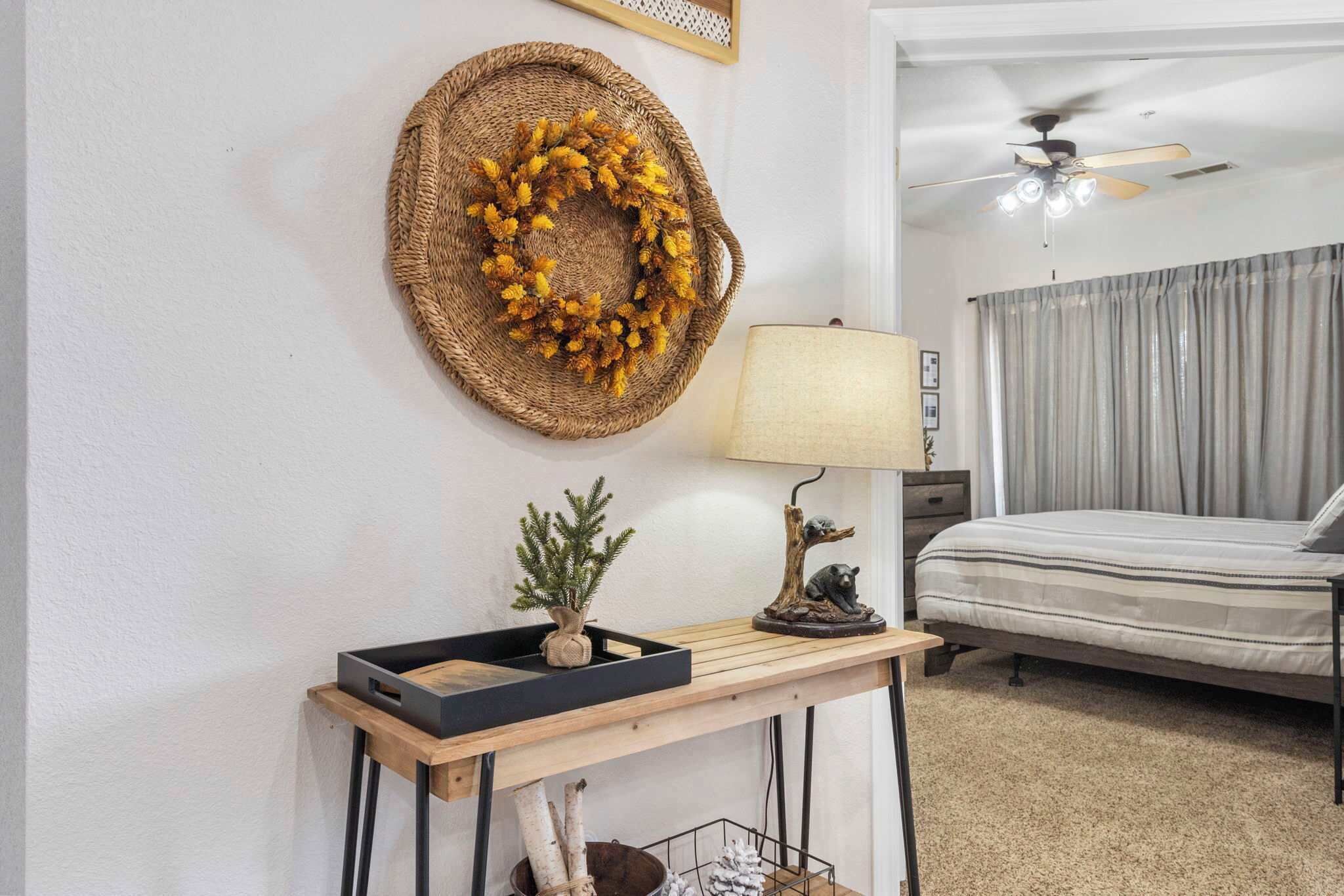 Un dormitorio con una cama, una mesita de noche con lámpara, una guirnalda decorativa y una pequeña planta de árbol.
