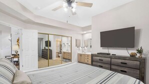 Une chambre avec un grand lit, une armoire, une télévision et un ventilateur de plafond.