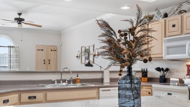 Une cuisine moderne dotée d’un îlot central, de meubles en bois et d’une branche de pin décorative servant de centre de table.