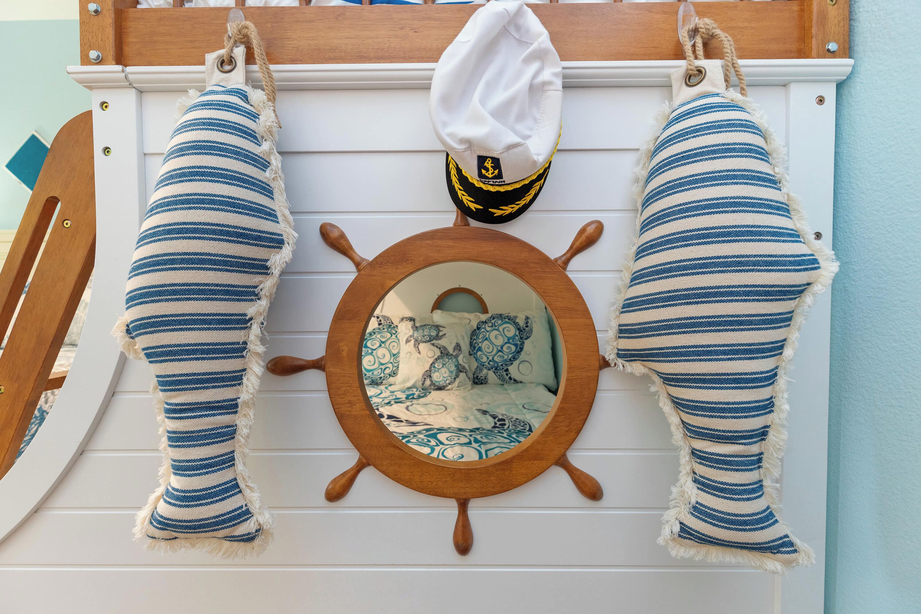 A nautical-themed wall decoration with a ship's wheel and striped cushions.