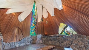 Un interior acogedor y rústico con un banco de piedra, un ventanal de vitrales y un techo de madera.