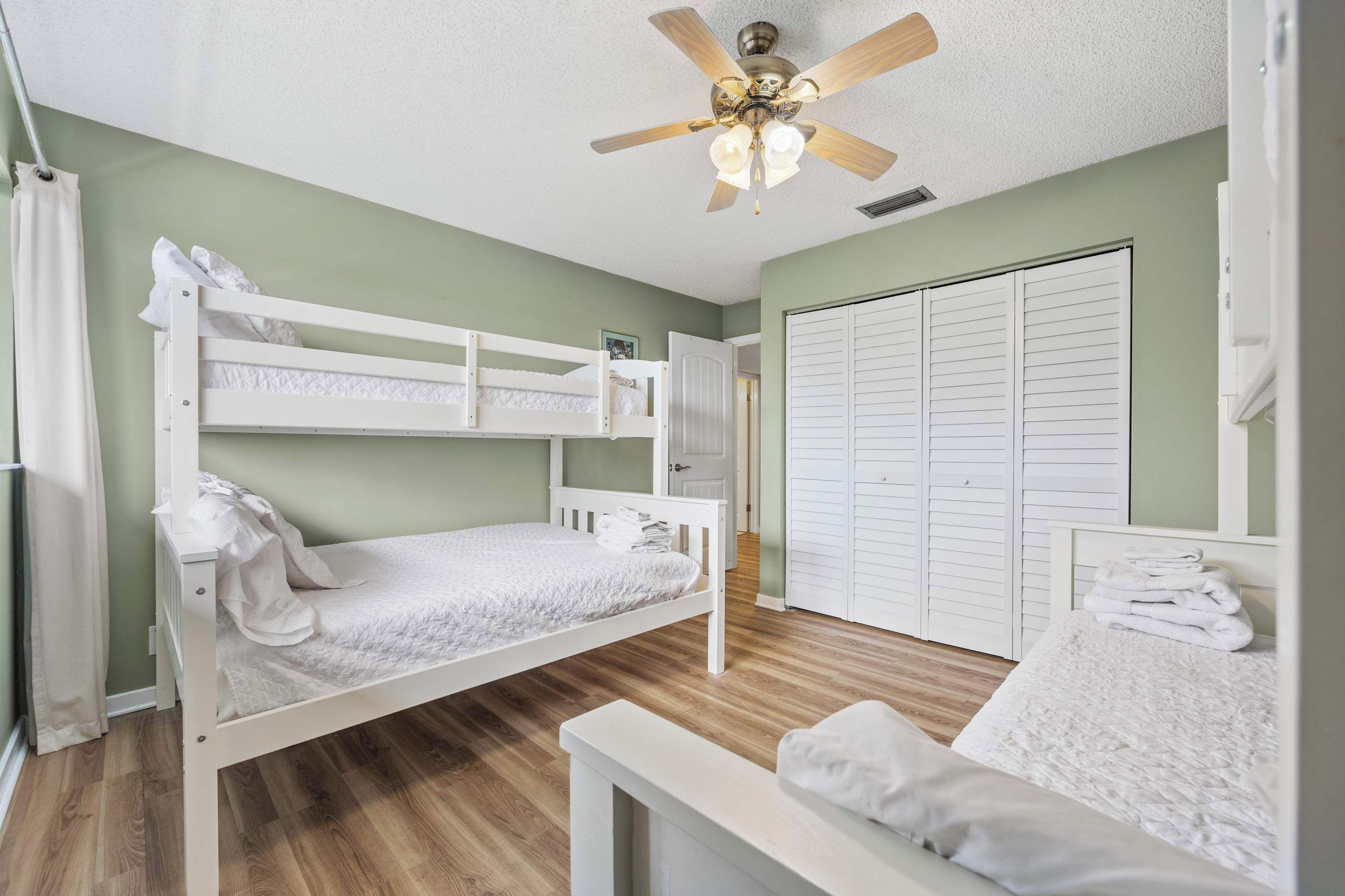 Habitación con literas, un ventilador de techo, un armario y una mesita.