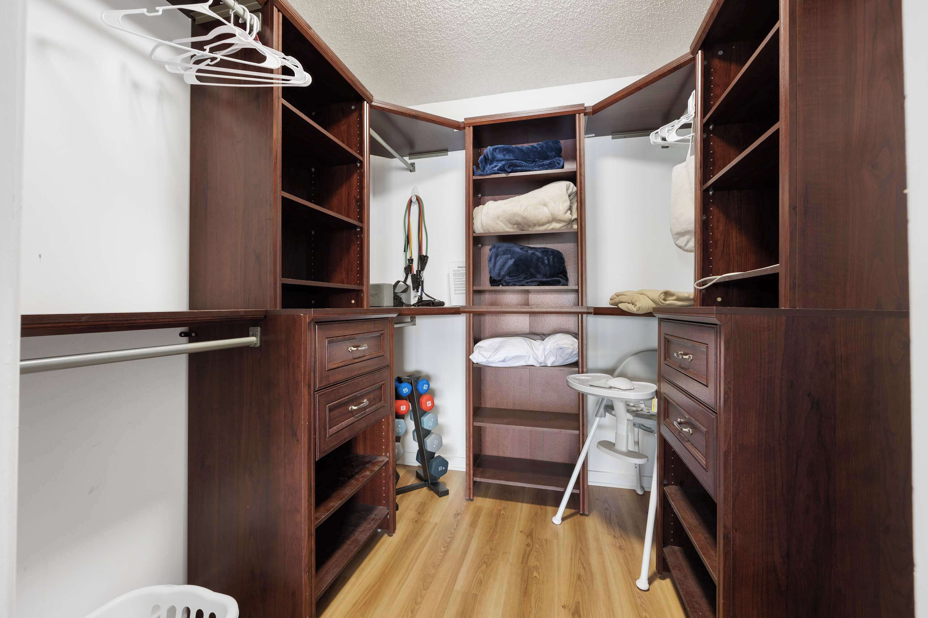 A compact, well-organized closet with multiple shelves and hanging space, a small table, and a shoe rack.