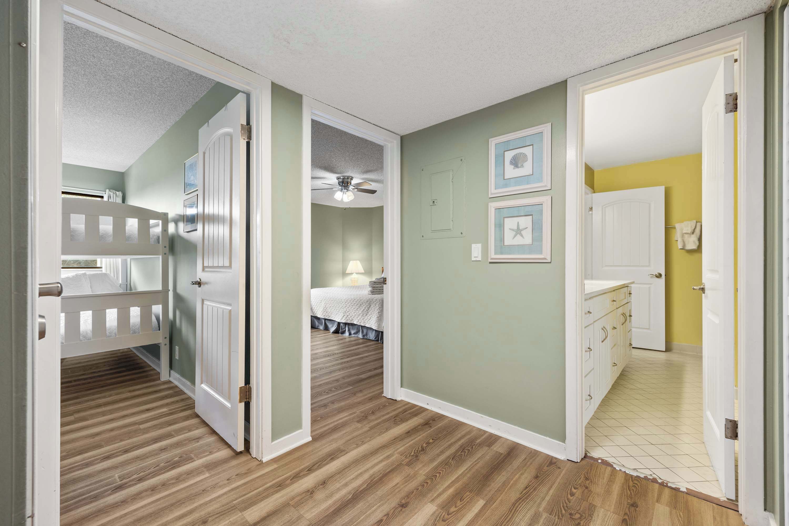 A hallway with a bunk bed, a ceiling fan, and a door leading to a bedroom.