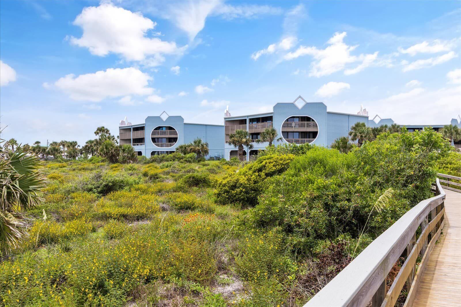 A resort with two buildings featuring circular balconies, surrounded by lush greenery and a wooden boardwalk.