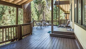 Una terraza de madera con sillones de descanso y vistas a un bosque.
