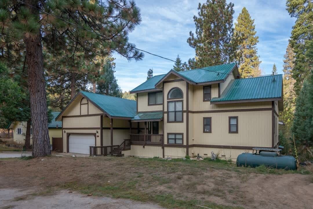 A two-story house with a green roof, a front porch, and a garage.