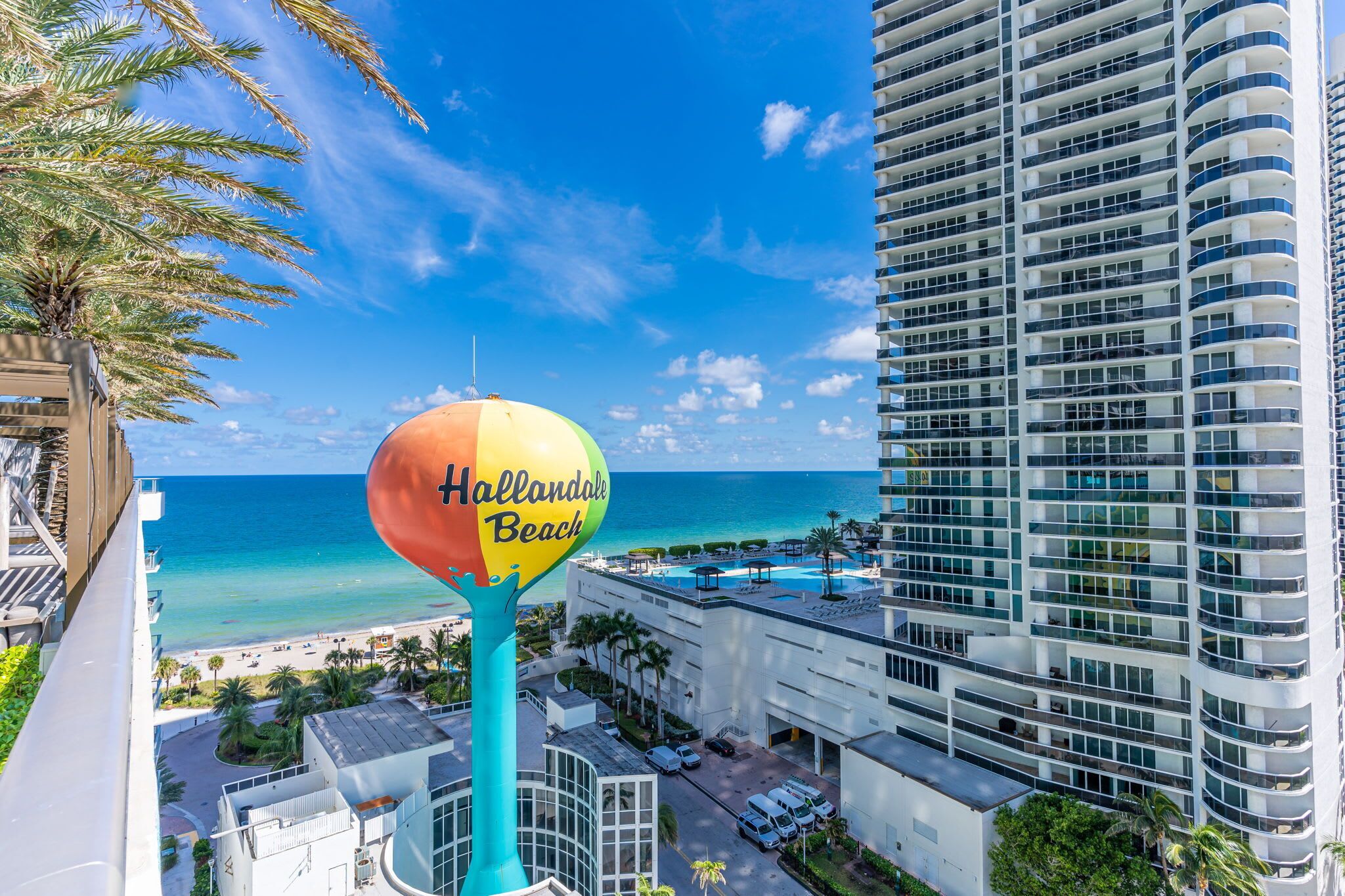 Vue de Hallandale Beach, avec un grand panneau, des immeubles de grande hauteur et un ciel bleu dégagé.