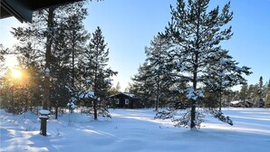 A cabin surrounded by snow-covered trees with a clear sky.