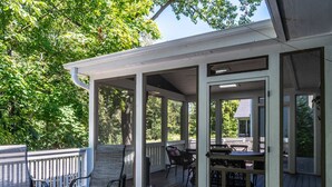 Une terrasse extérieure couverte, dotée de sièges et d’une table, et entourée d’arbres.