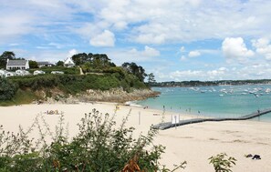 A beach with a sandy shore, a pier, and a backdrop of houses and boats. - Beautiful home in Plougonvelin (Plougonvelin)