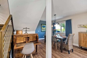 A dining area with a wooden table, chairs, and a hanging light fixture.