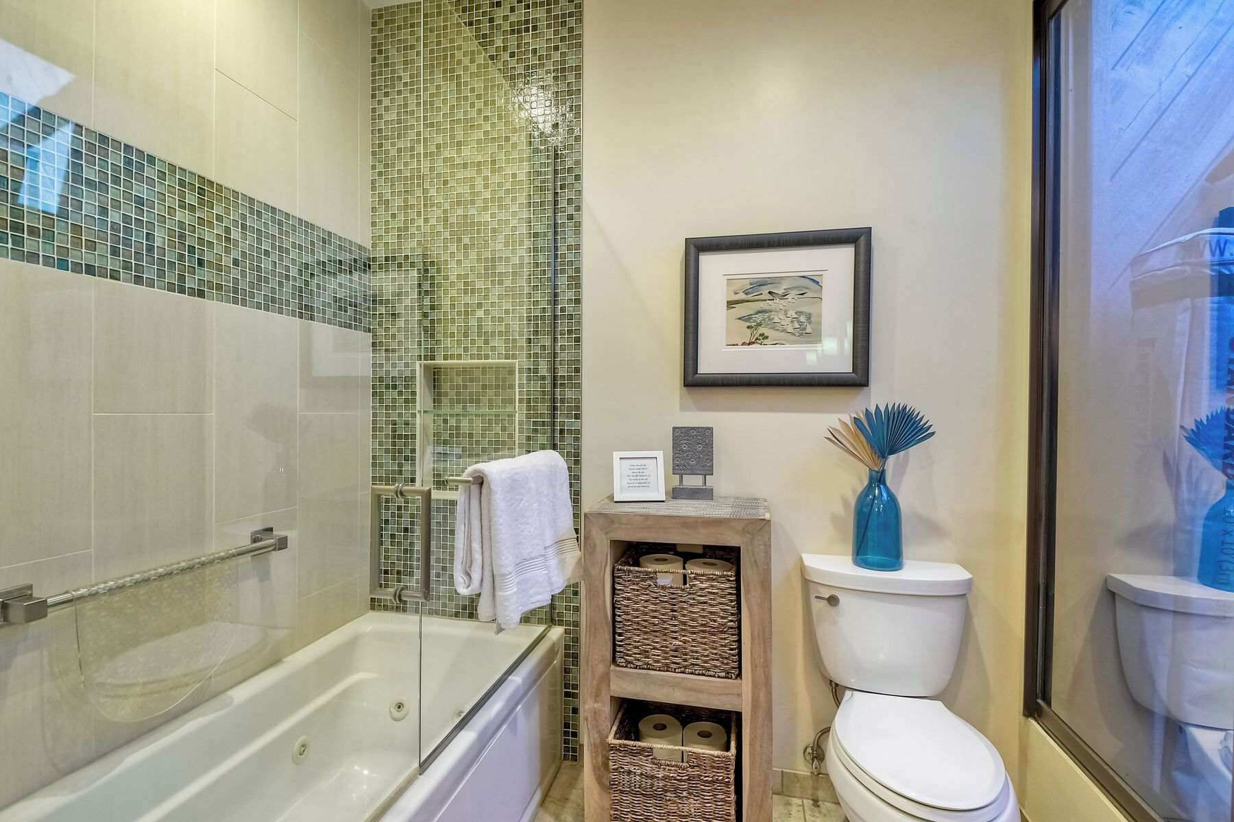 A bathroom with a glass-enclosed shower, a white toilet, and a framed picture on the wall.