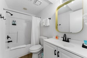 Une salle de bain équipée d’une douche, de toilettes, d’un lavabo et d’un miroir avec un cadre doré.