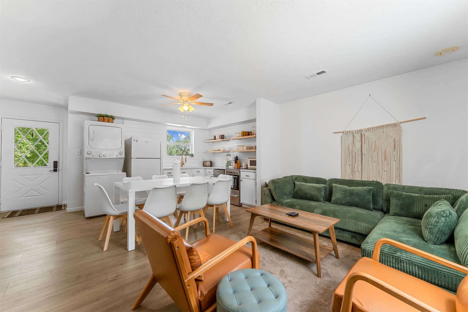 A compact living space with a kitchenette, dining area, and a green sofa.