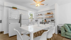 Une cuisine moderne avec des appareils électroménagers blancs, une table à manger avec des chaises et un ventilateur de plafond.