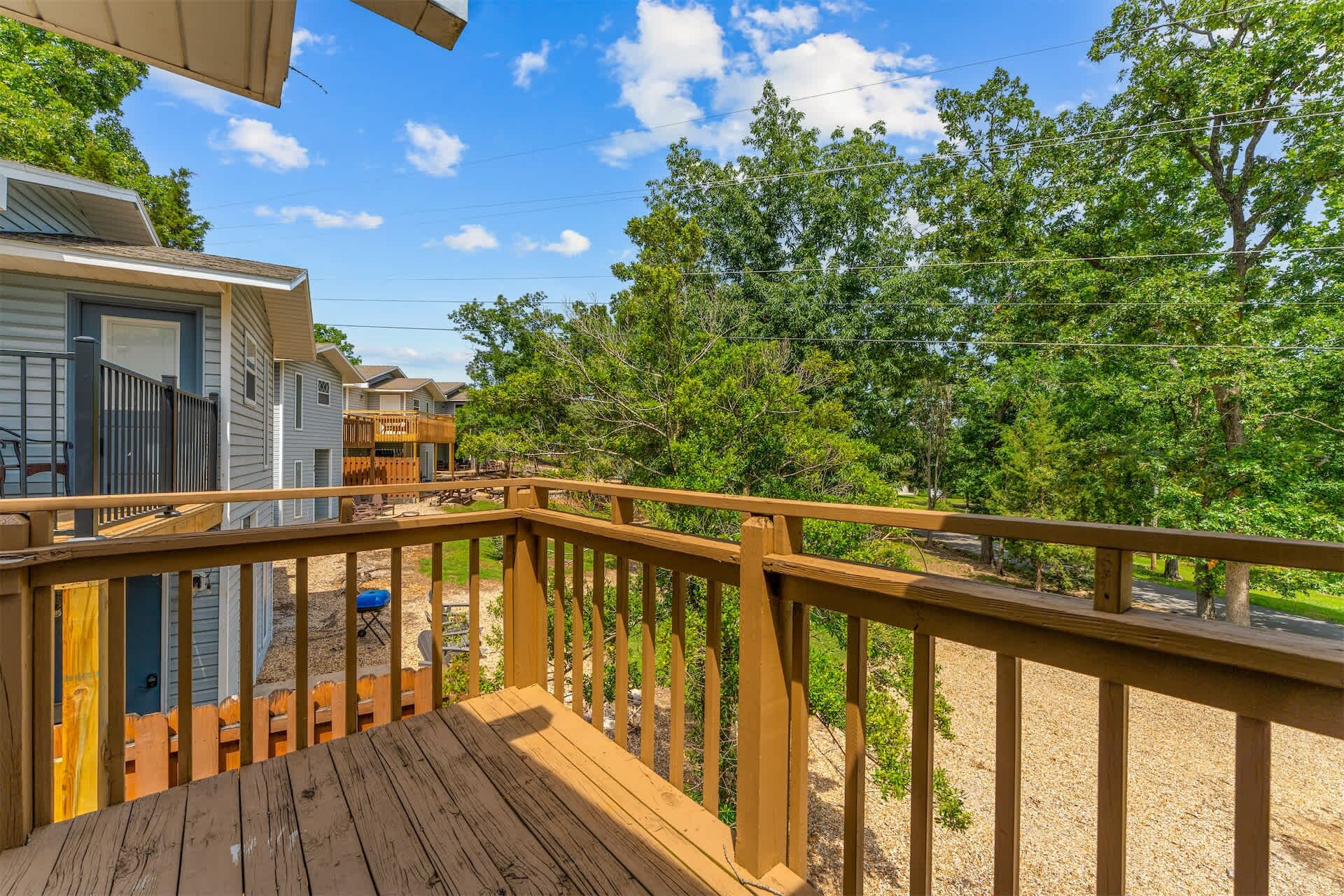 A wooden deck with a view of a residential area, including houses and trees.