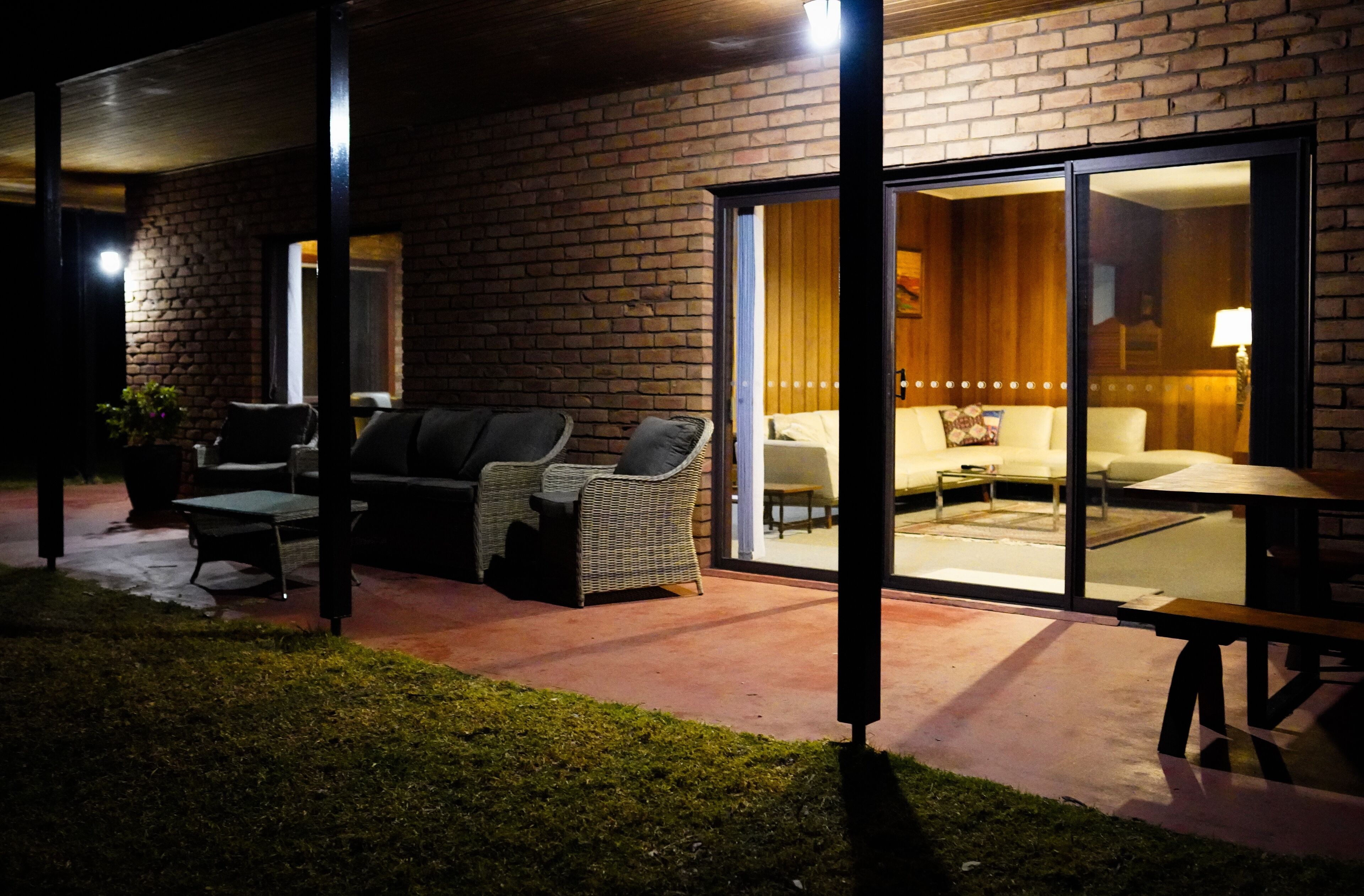 A brick house with a patio area featuring outdoor furniture and a glass door leading to an interior space with a sofa and a table.