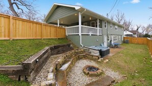A house with a covered porch, a stone fire pit, and a backyard with a wooden fence.