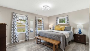 A bedroom with a bed, bedside tables, a bench, and curtains.