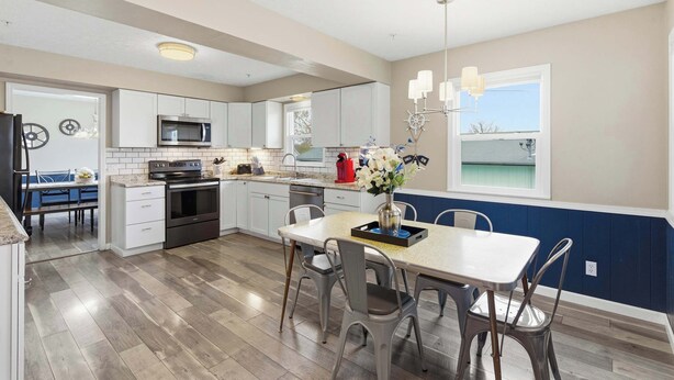 A modern kitchen with white cabinets, a microwave, and a dining area with a table and chairs.