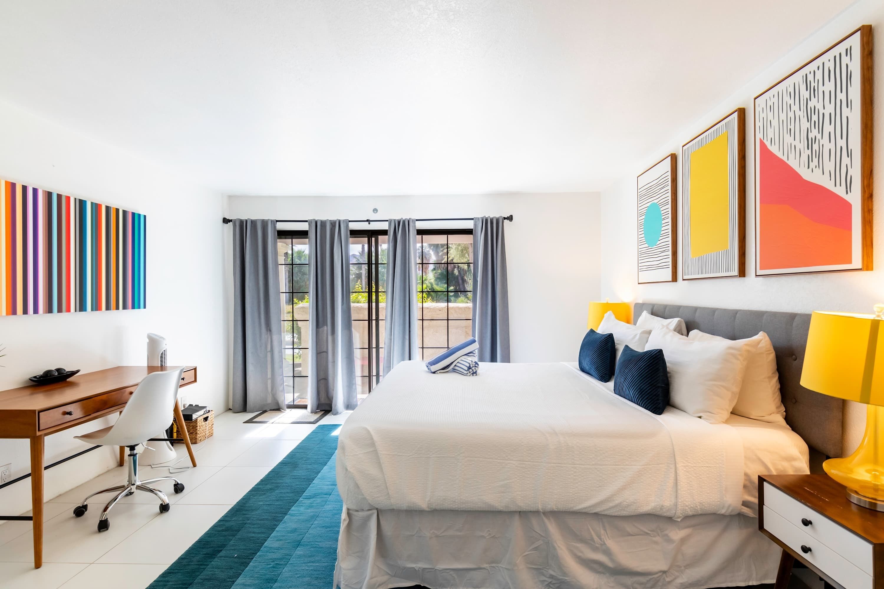 Ein modernes Hotelzimmer mit einem großen Bett, einem Schreibtisch und Blick ins Freie.
