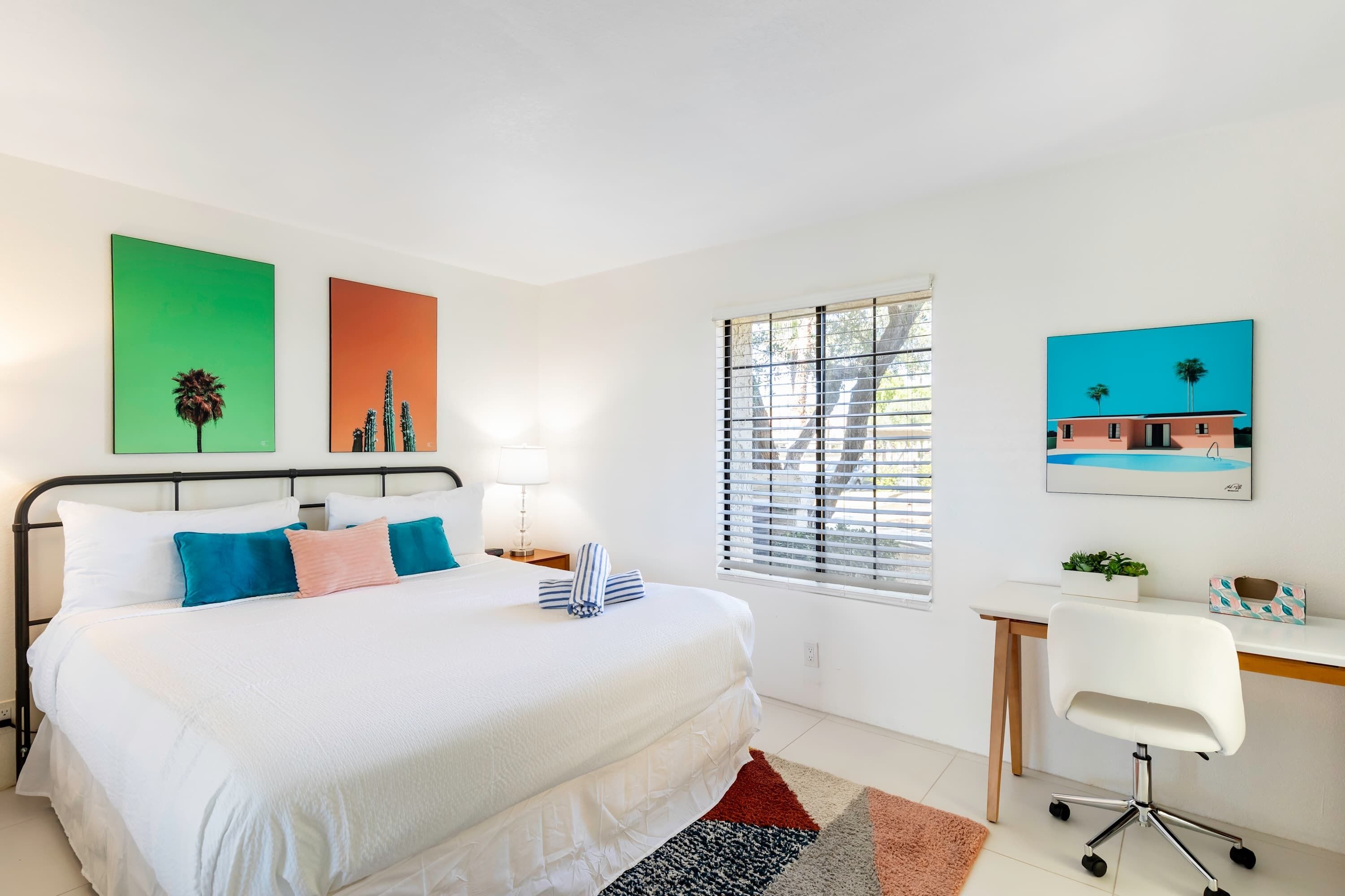 Un dormitorio moderno con una cama grande, un escritorio y una ventana con persianas.