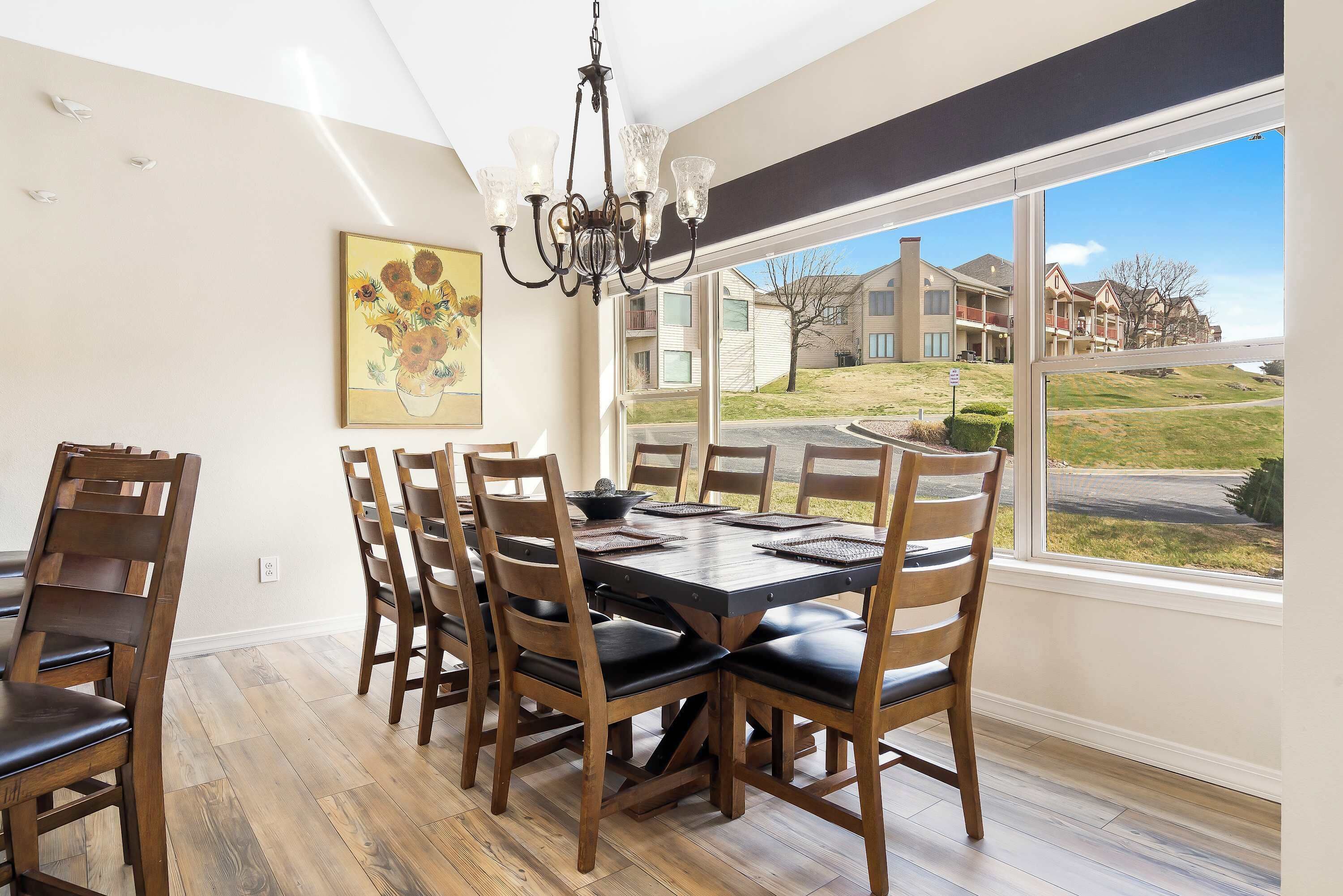 A dining area with a large table, wooden chairs, and a chandelier.