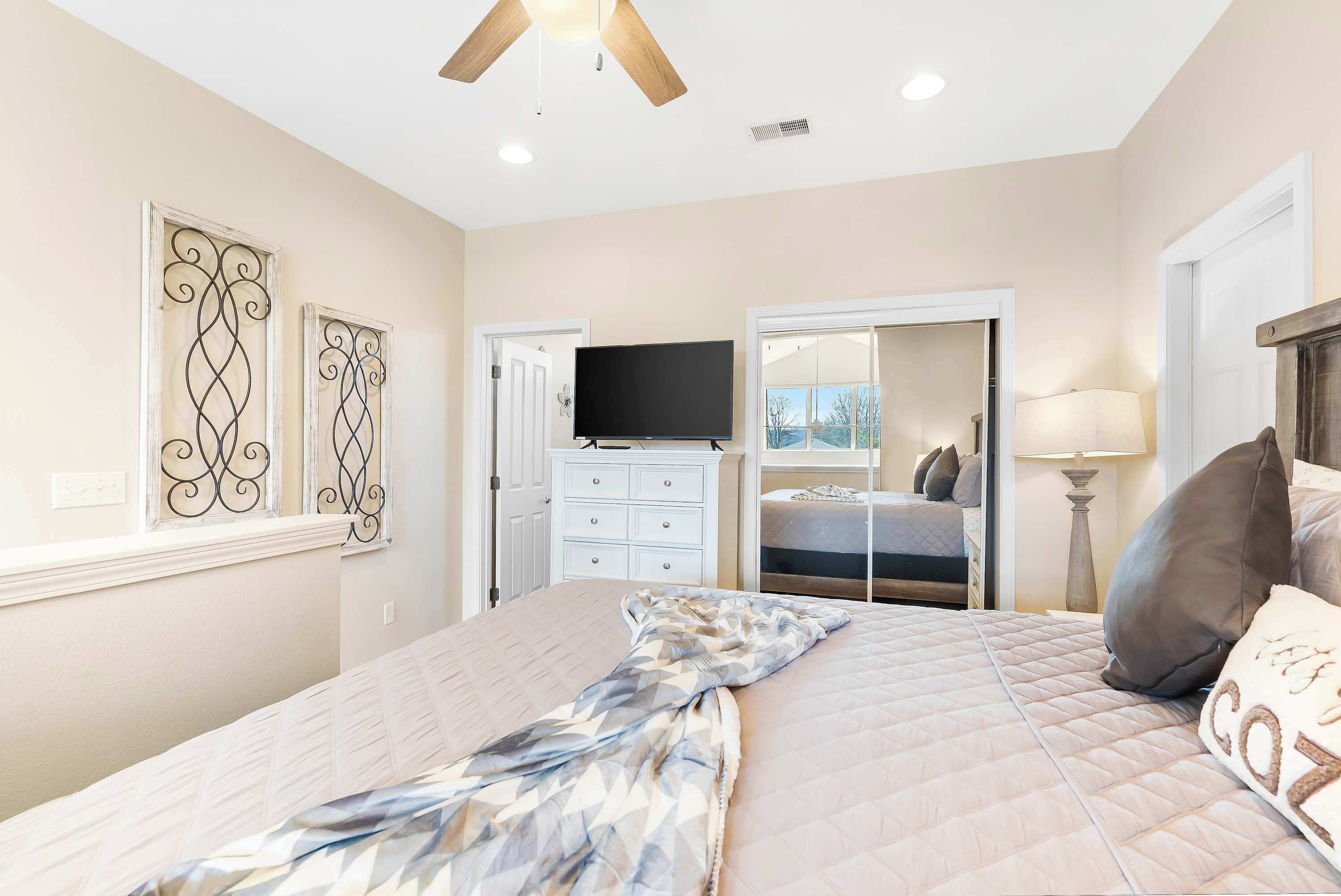 A bedroom with a bed, a TV, a dresser, and a closet.