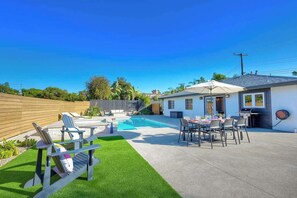 A backyard with a swimming pool, patio furniture, and a barbecue area.