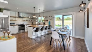 Una cocina moderna con una isla central, taburetes de bar y una mesa de comedor preparada para seis personas.