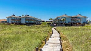 A pathway leading to a beachfront property with multiple balconies and a clear view of the ocean. - Resort Pool & Clear Ocean Views (Port Aransas)