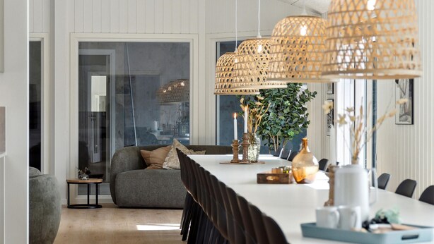 A modern dining area with a long table, wicker pendant lights, and a plant in the background. - Awesome home in ålbæk with WiFi (Ålbæk)