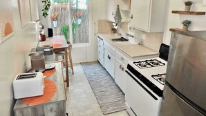 Una cocina moderna con armarios blancos, una estufa a gas, un fregadero y un comedor con mesa y sillas.