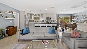 Un salon moderne avec un canapé gris, une table basse et un coin repas comprenant une table et des chaises.
