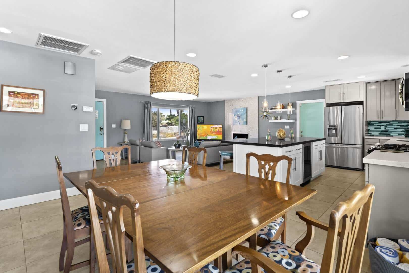 A modern kitchen with a central island, stainless steel appliances, and a dining area with a wooden table and chairs.