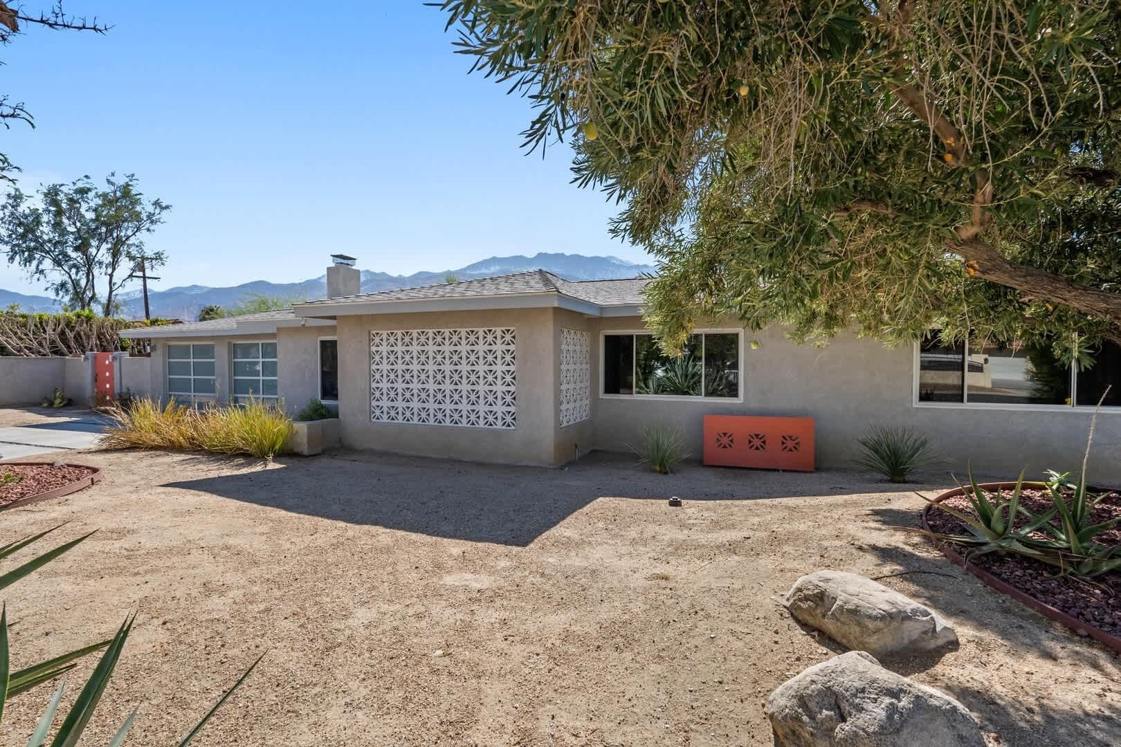 Une maison moderne dotée d’un garage, d’un mur décoratif et d’un jardin bien entretenu.