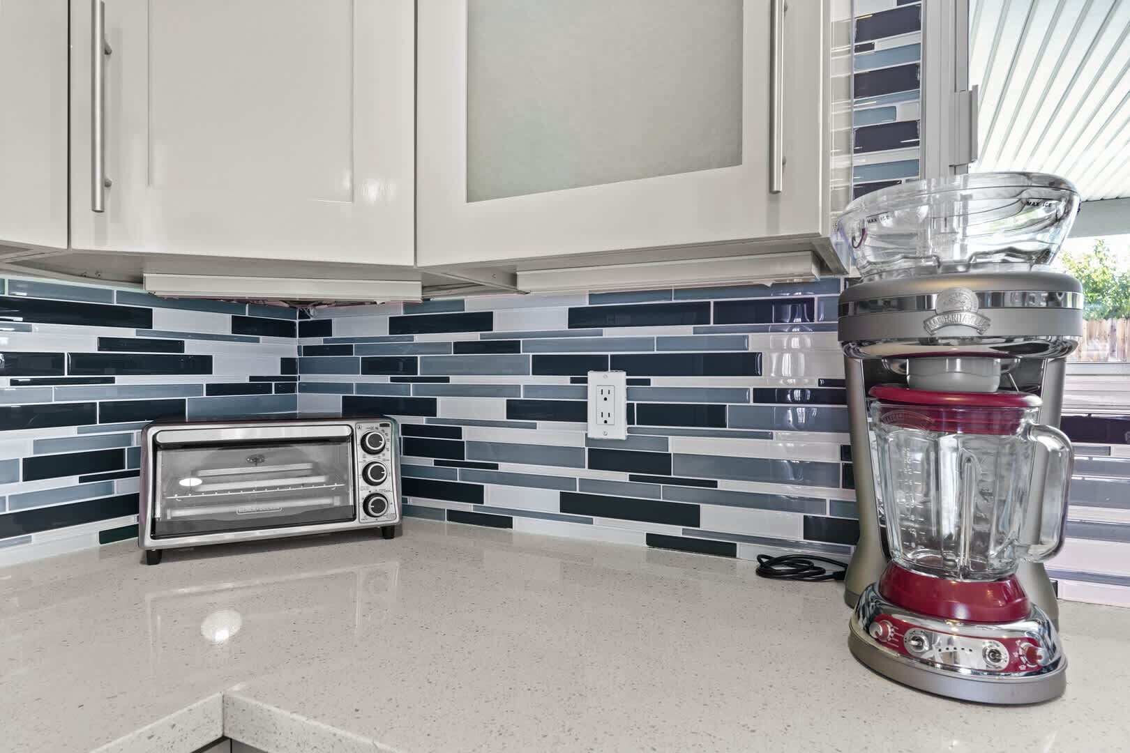 A kitchen with white cabinets, a toaster, and a blender on the counter.