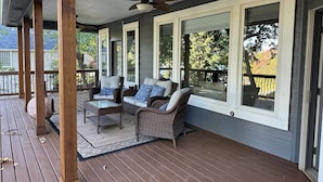 A covered porch with wicker furniture, large windows, and a ceiling fan.