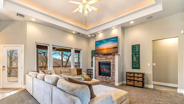 A spacious living room with a large sectional sofa, a fireplace, and a view of the outdoors through large windows.