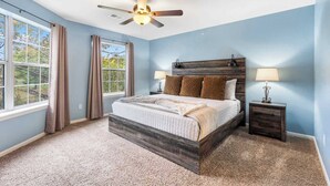 A bedroom with a bed, two bedside tables, a ceiling fan, and large windows. - Dora - Holiday Hills Branson - Golf Resort - Branson - Outdoor Pools (Branson)