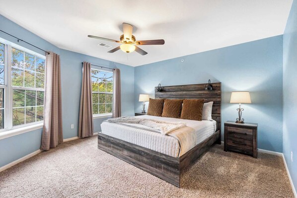 A bedroom with a bed, two bedside tables, a ceiling fan, and large windows. - Dora - Holiday Hills Branson - Golf Resort - Branson - Outdoor Pools (Branson)