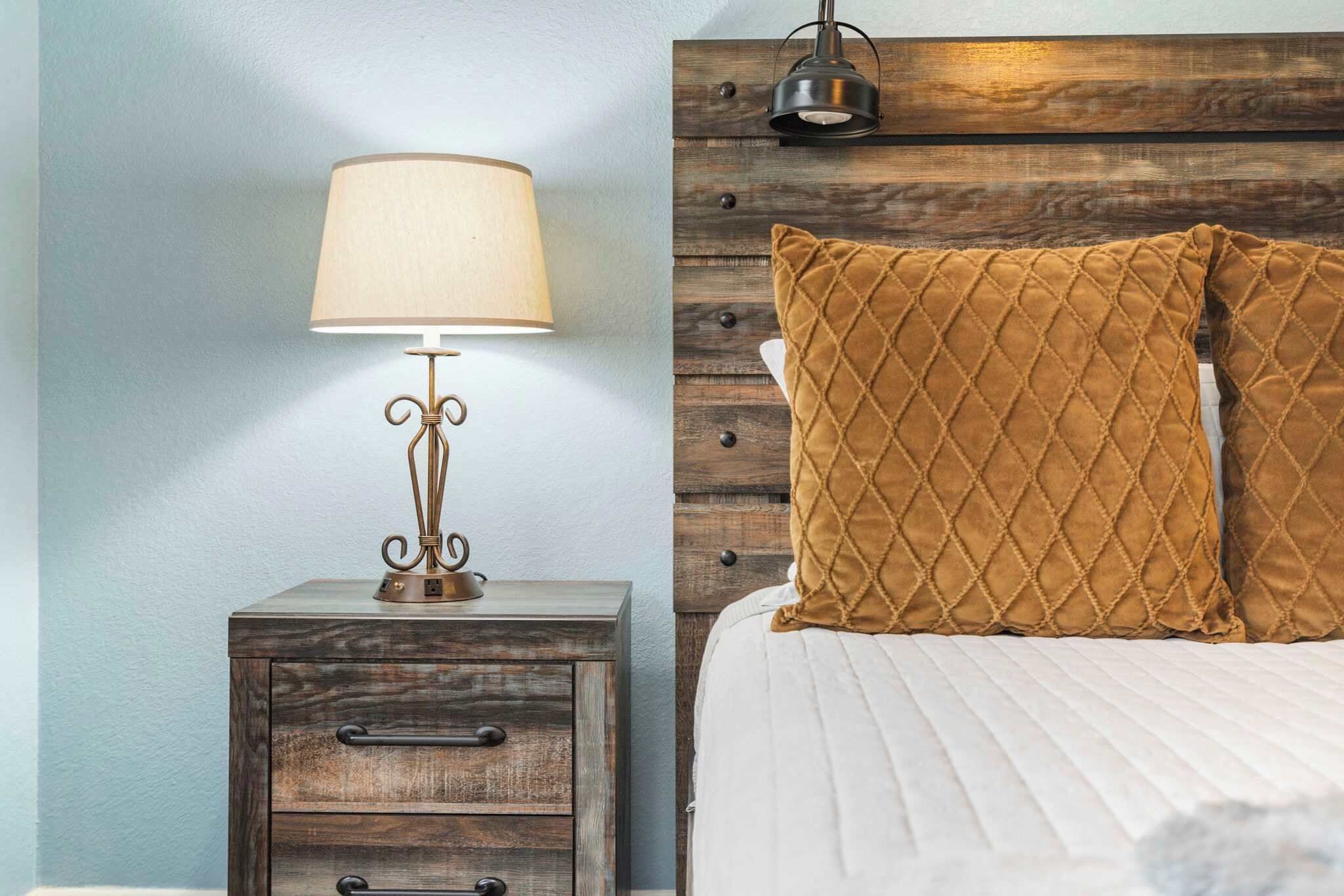 Une chambre à coucher avec une tête de lit en bois, une lampe de chevet et deux coussins matelassés.