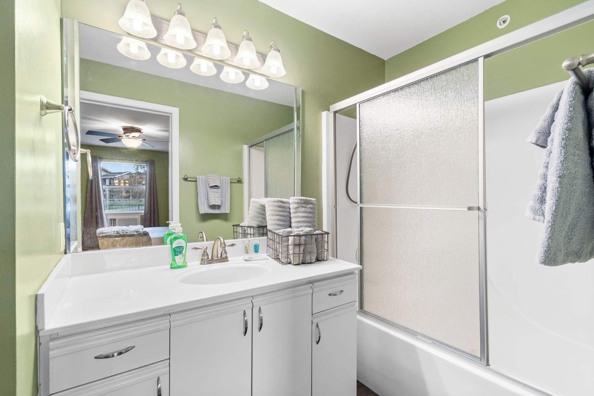 A bathroom with a white vanity, a large mirror, and a shower enclosure.