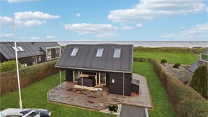Una casa moderna con techo inclinado, ventanas amplias y una terraza.