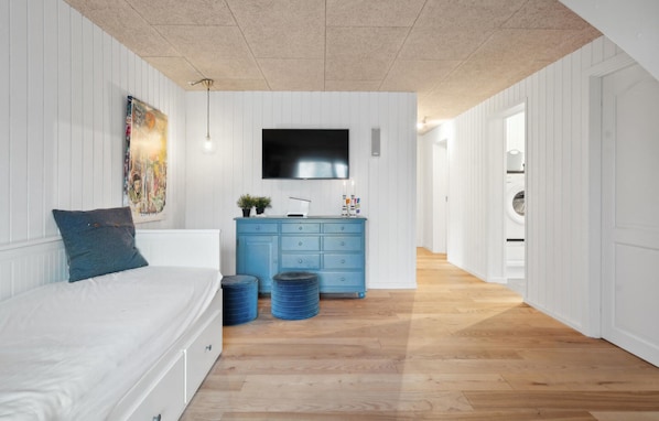 Un dormitorio con una cama, un aparador, un televisor y un cuadro en la pared.