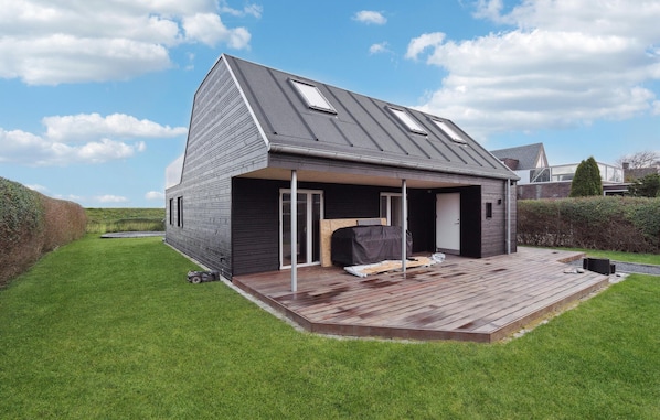 A modern house with a sloped roof, a covered porch, and a wooden deck.