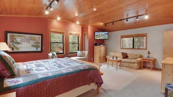 A bedroom with a large bed, a dresser, a sofa, and a television.